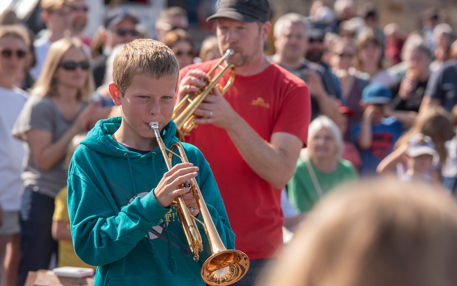 A young boy in a bright blue hoodie playing a trumpet