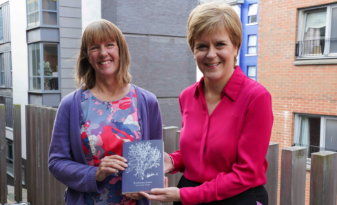 First Minister Nicola Sturgeon standing with newly appointed Makar Kathleen Jamie - they are both smiling and holding a book
