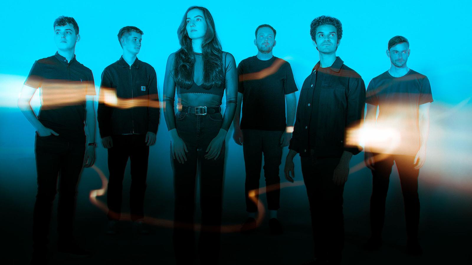 A band stand against a wall flooded with blue light