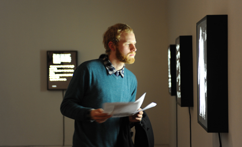 A man stands in front of a lightbox in a gallery