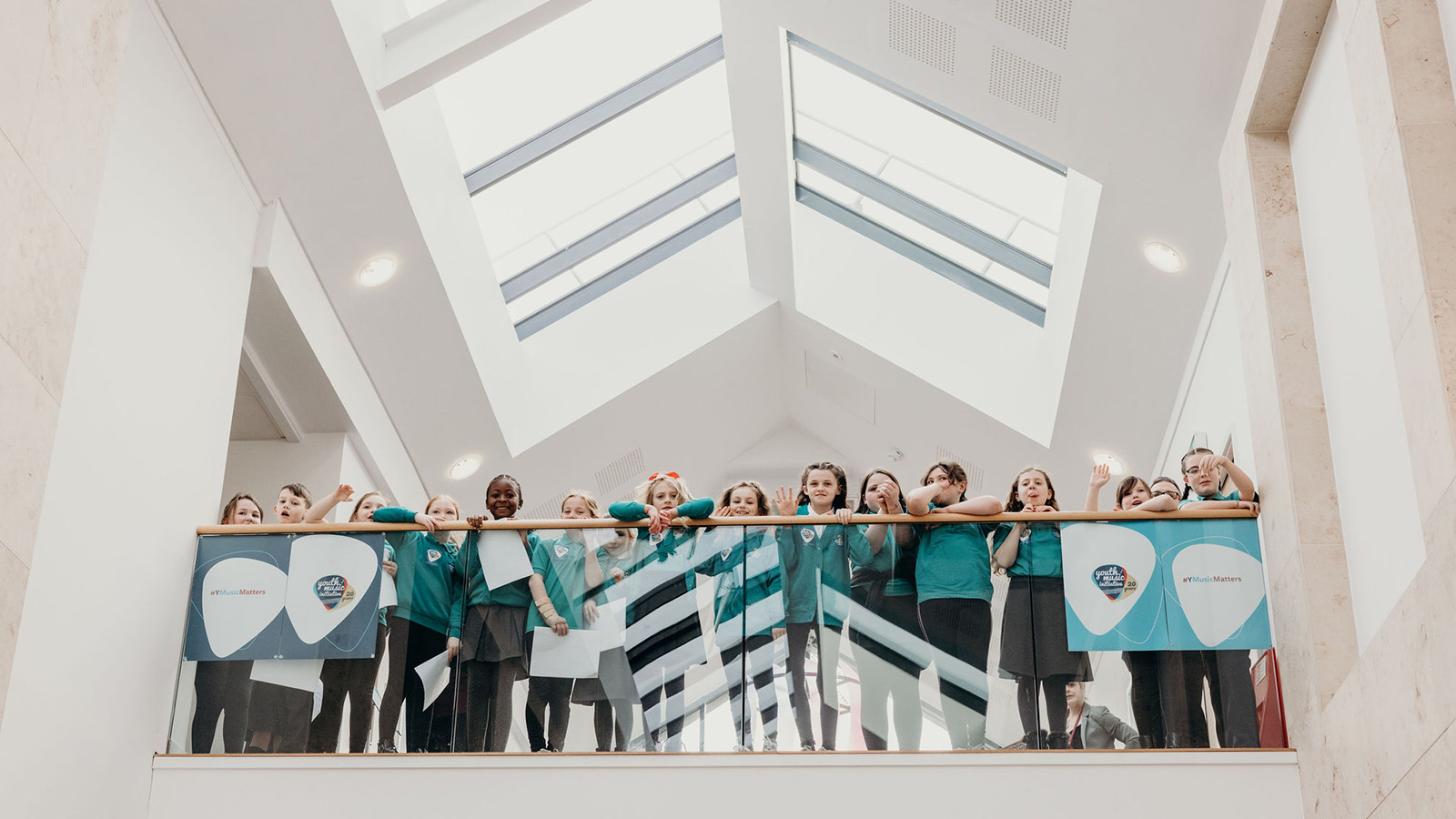 Young children in school uniform look down from a balcony. Image by Venture Creative for YMI.