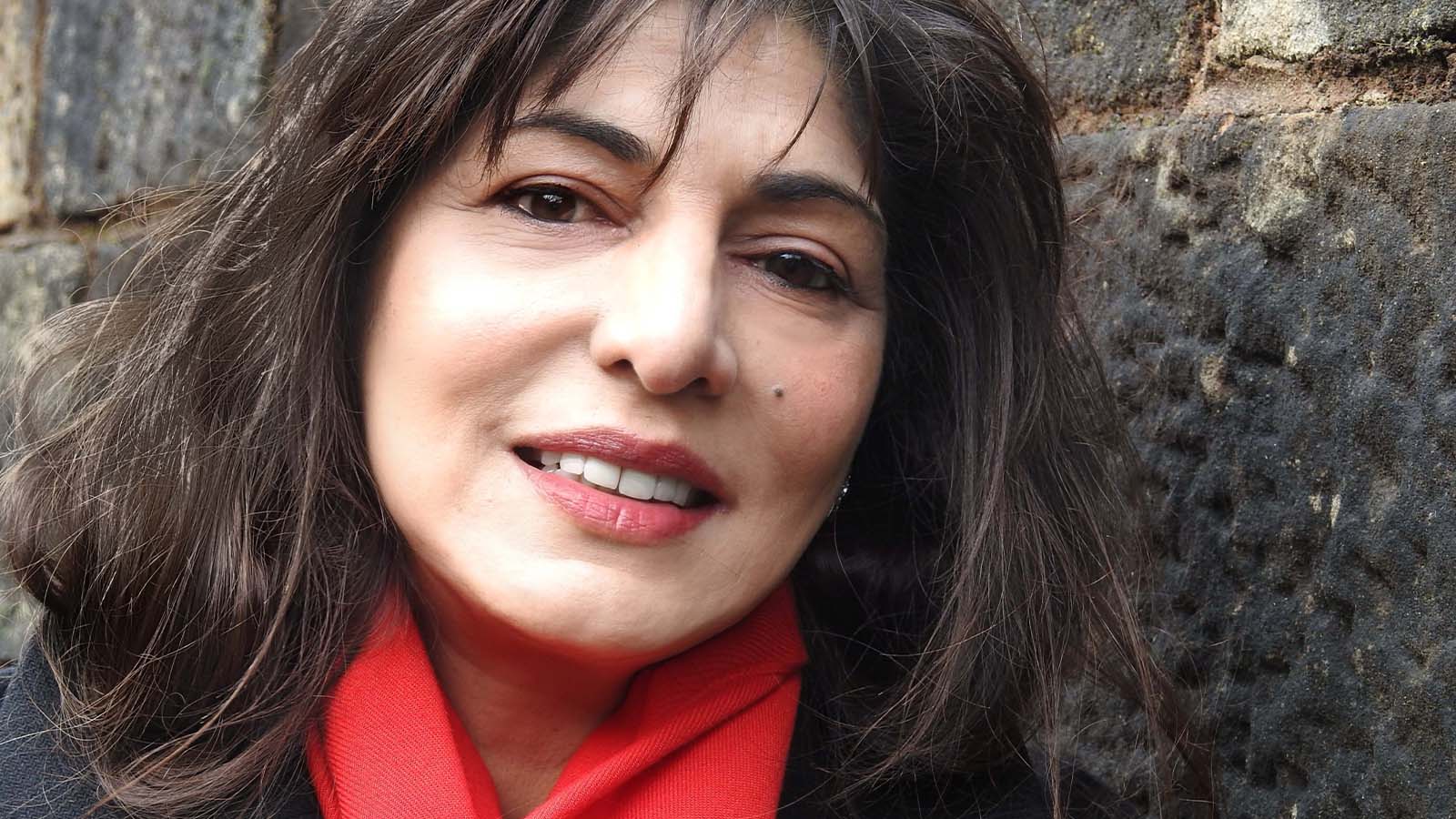 A woman with dark brown hair and a fringe, wearing a red scarf - Ashe Hussain