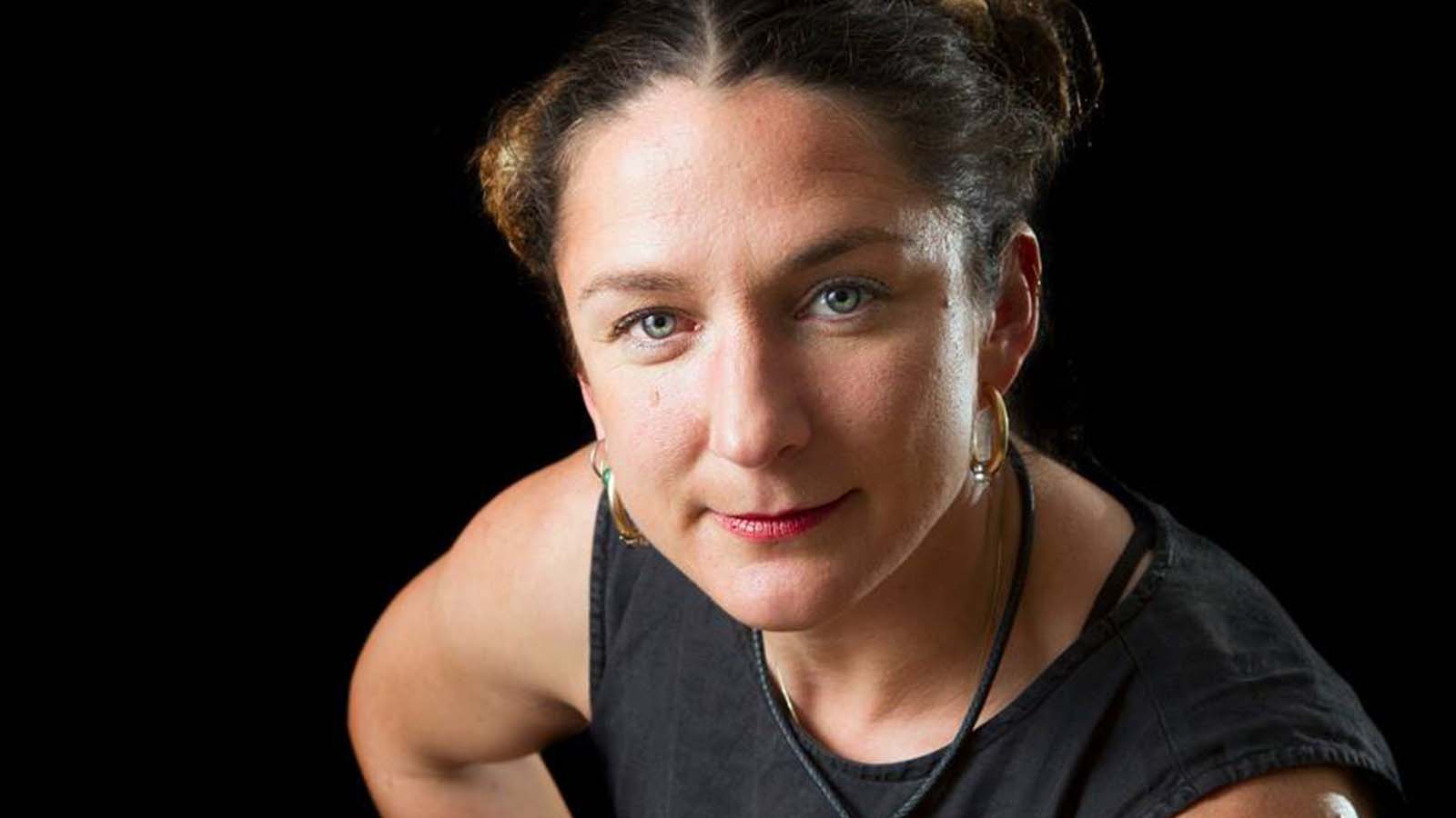 A woman with short hair tied back, wearing a dark coloured sleeveless top. This is Cate Ross.