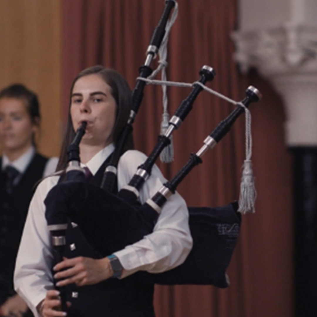 A young woman is pictured playing the bagpipes during a performance