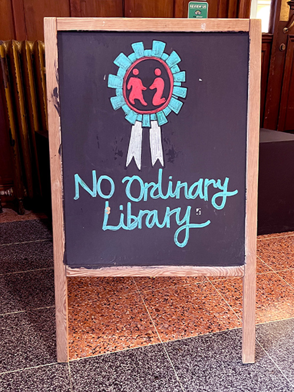 A wooden sign that says No Ordinary Library - it's in the entryway of Glasgow Women's Library