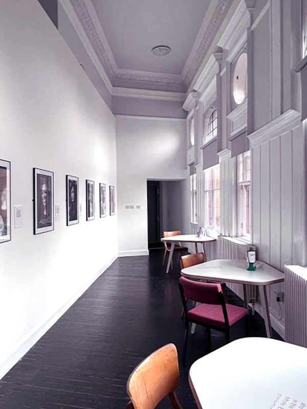 A bright white room upstairs at Glasgow Women's Library feels airy and light, with tables and black and white portrait photography on the wall