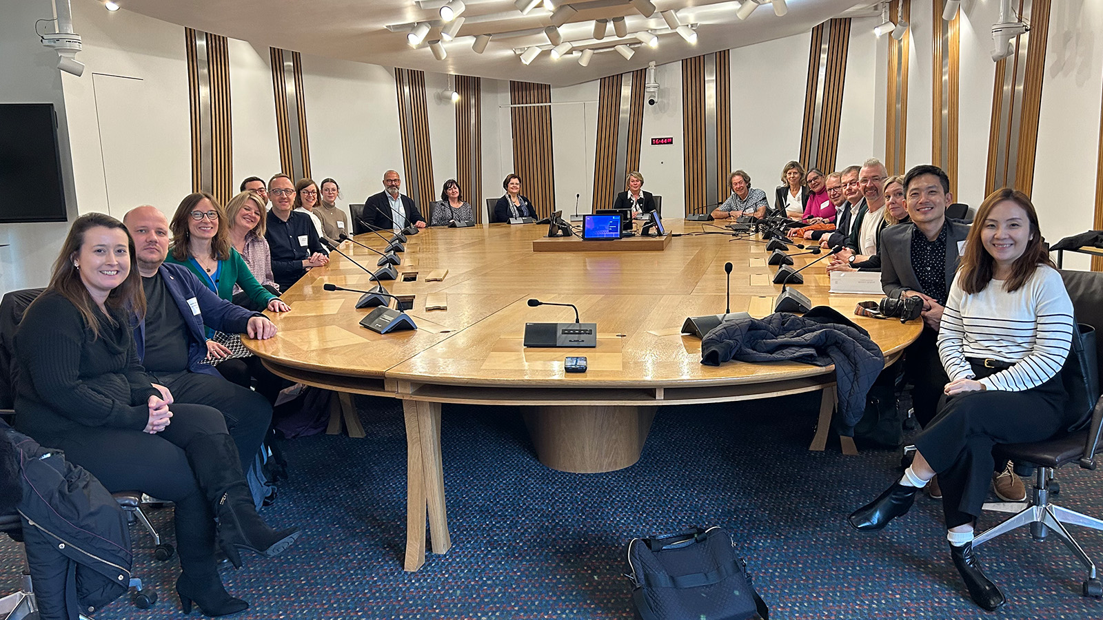 A group of people sitting together around a large wooden table inside The Scottish Parliament