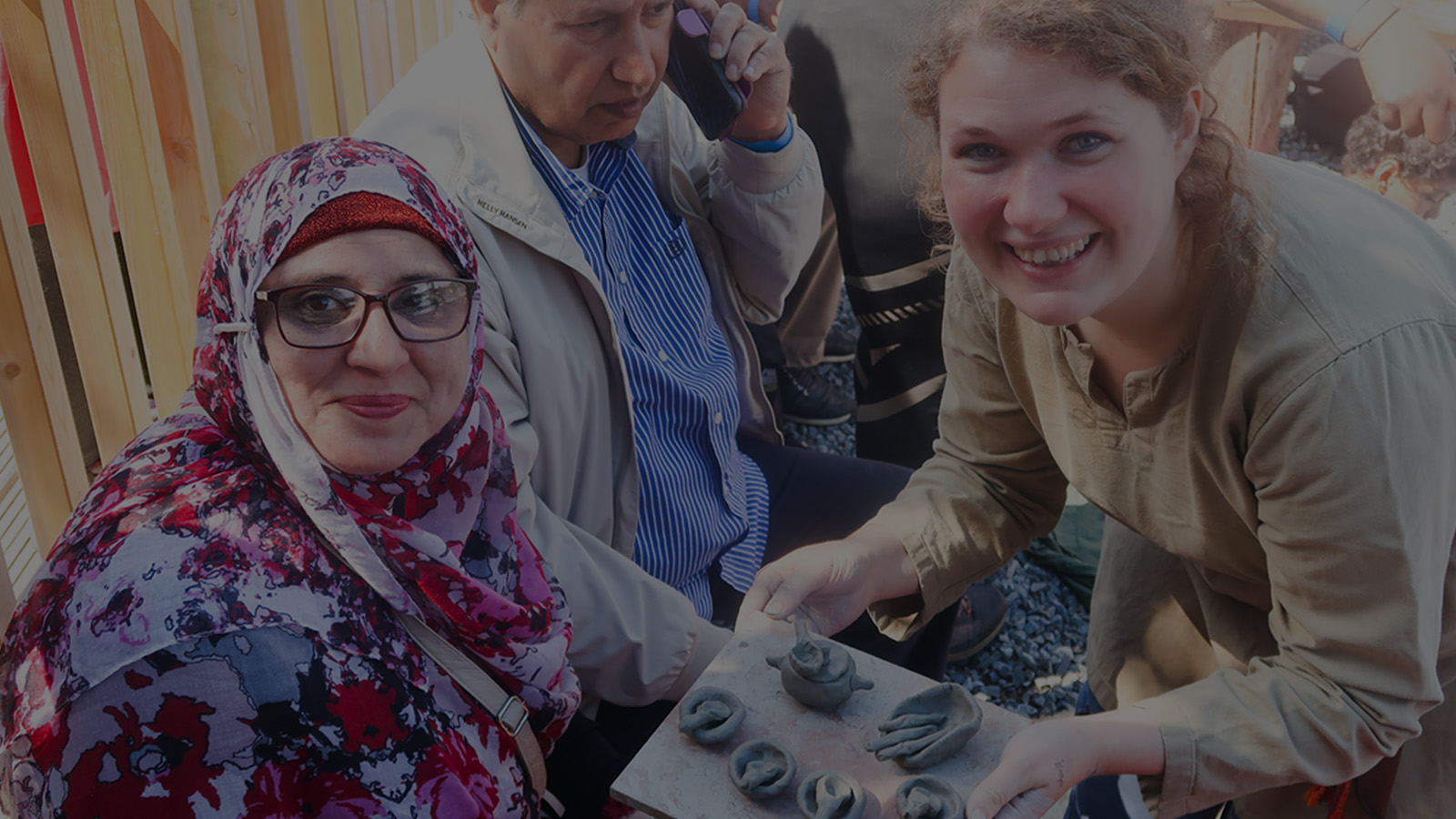 Two women smile at the camera holding pottery in progress