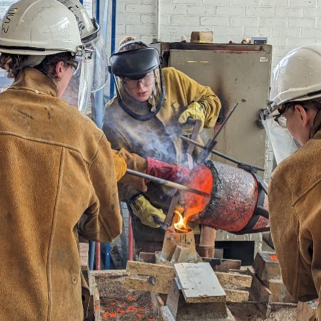 Kathryn Hanna at work in her studio, pouring out hot liquid material  while wearing protective gear