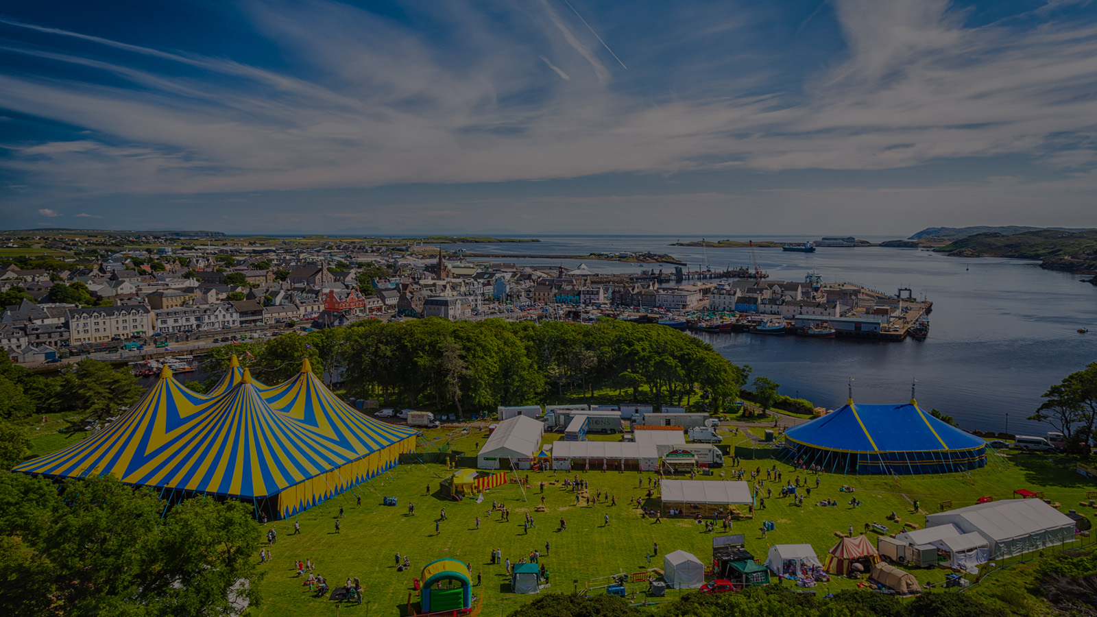 The HebCelt festival as seen from the sky. Several large colourful tents dots a green landscape filled with crowds on a a bright sunny day.
