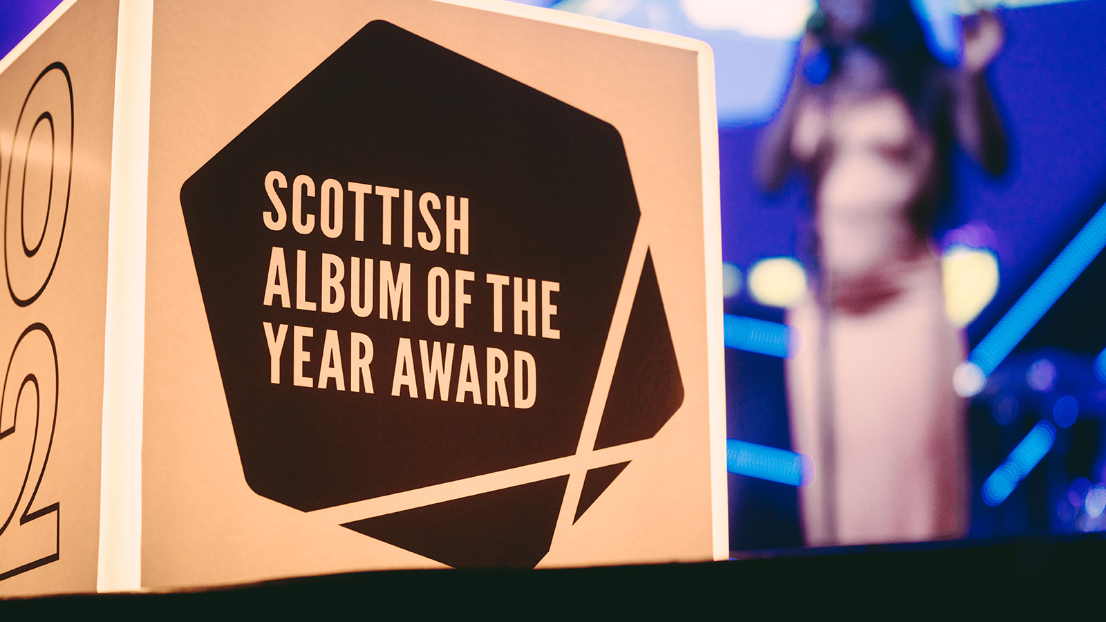 Close-up of the SAY Award trophy, Artist AiiTee performs in the background