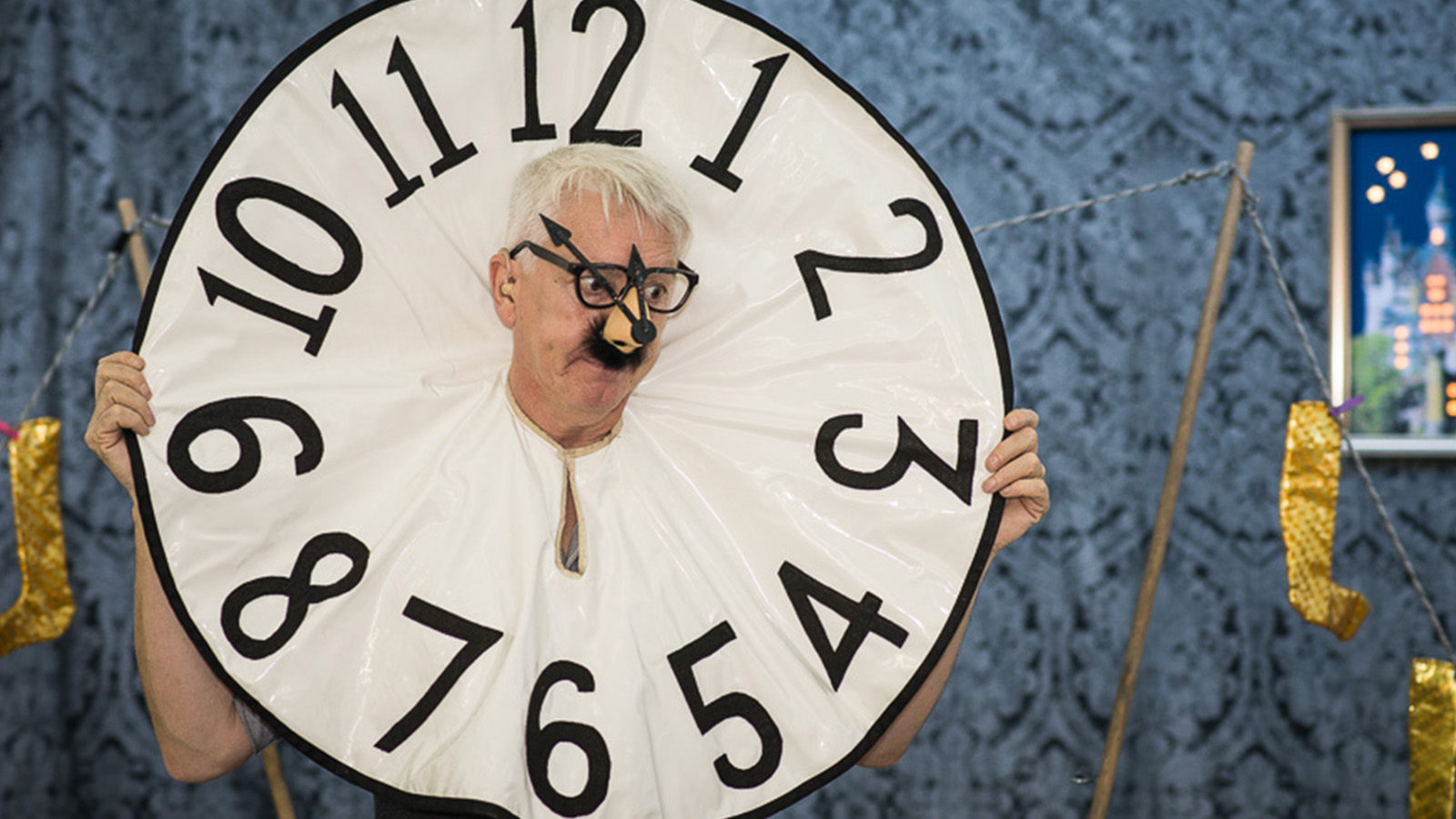 A man wearing a giant clock made of cloth around his neck