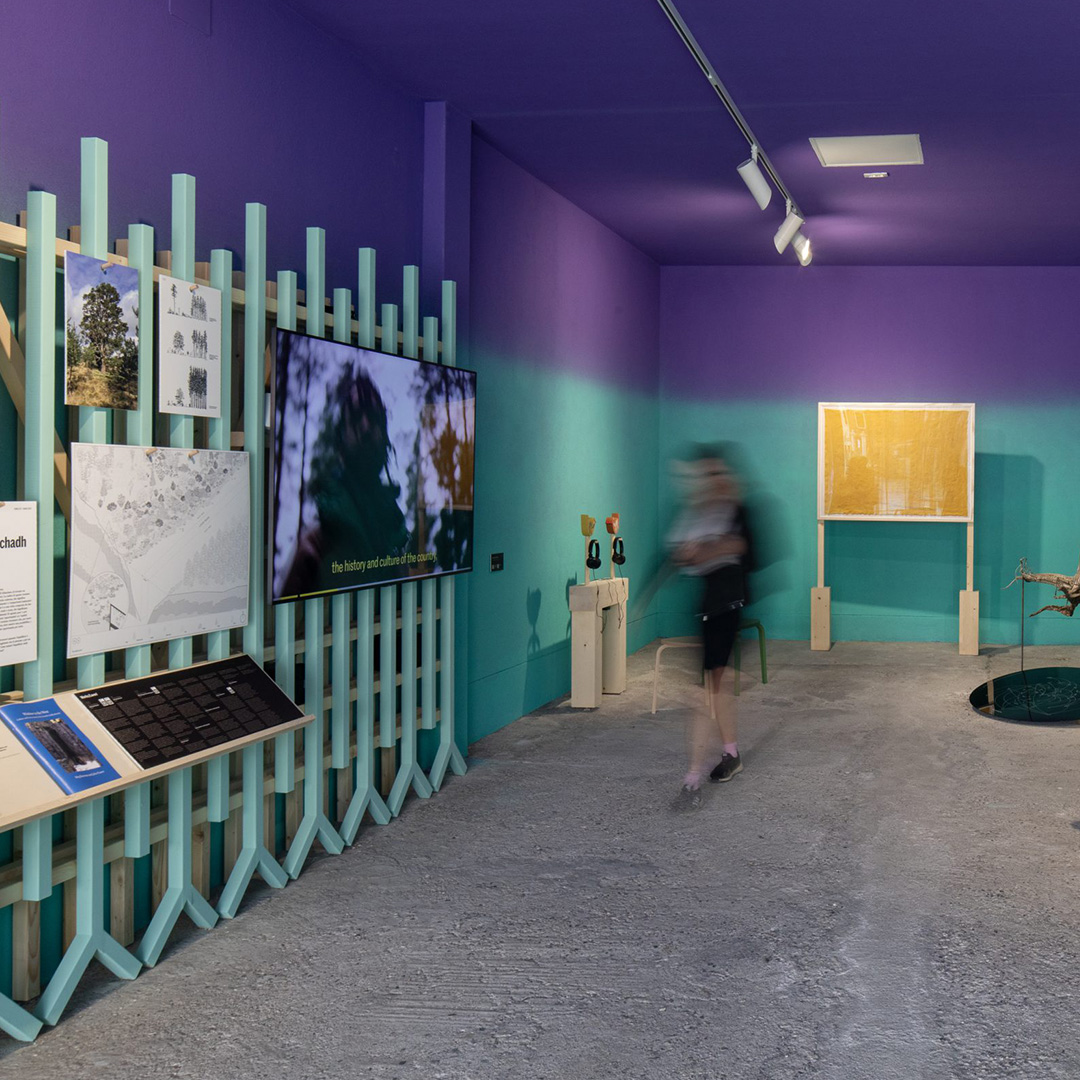 Photograph of the exhibition with a blurry person walking through the space
