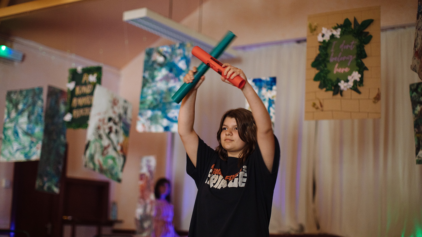 A young girl stands holding sticks in front of her