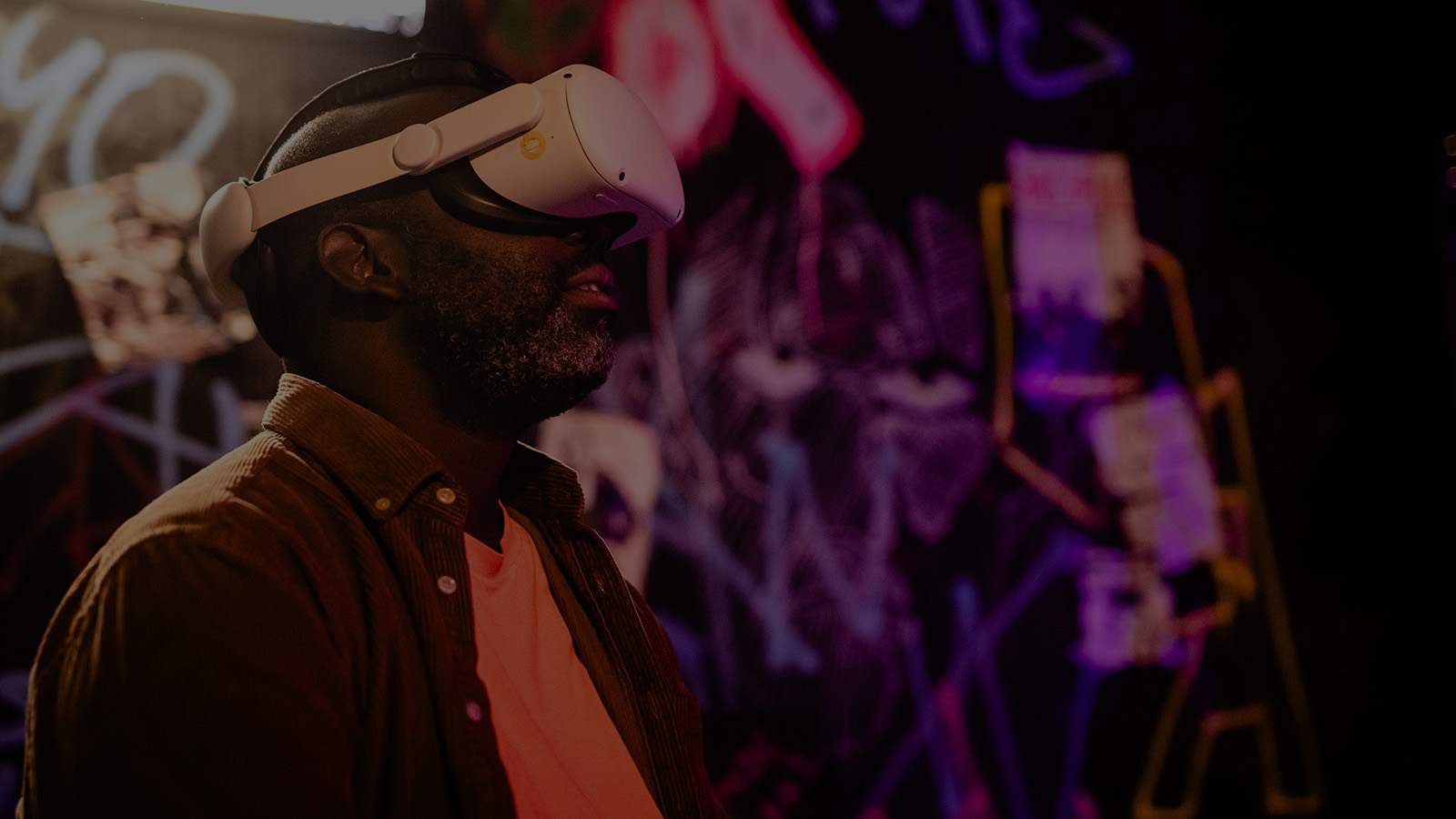 A man wearing VR goggle in a room with walls covered in brightly coloured neon paint