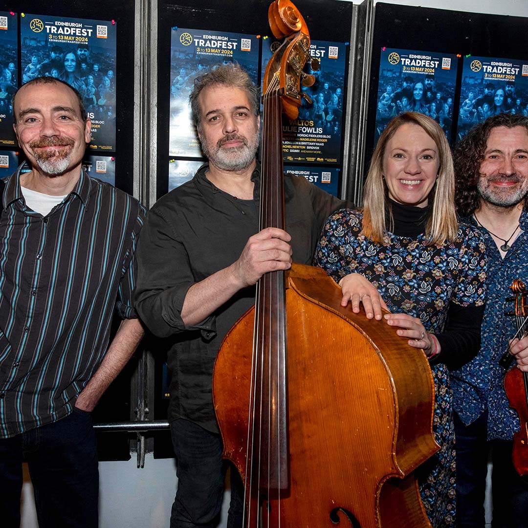 Four people - three man with instruments and a woman - pictured together in front of a wall of posters for Edinburgh tradfest