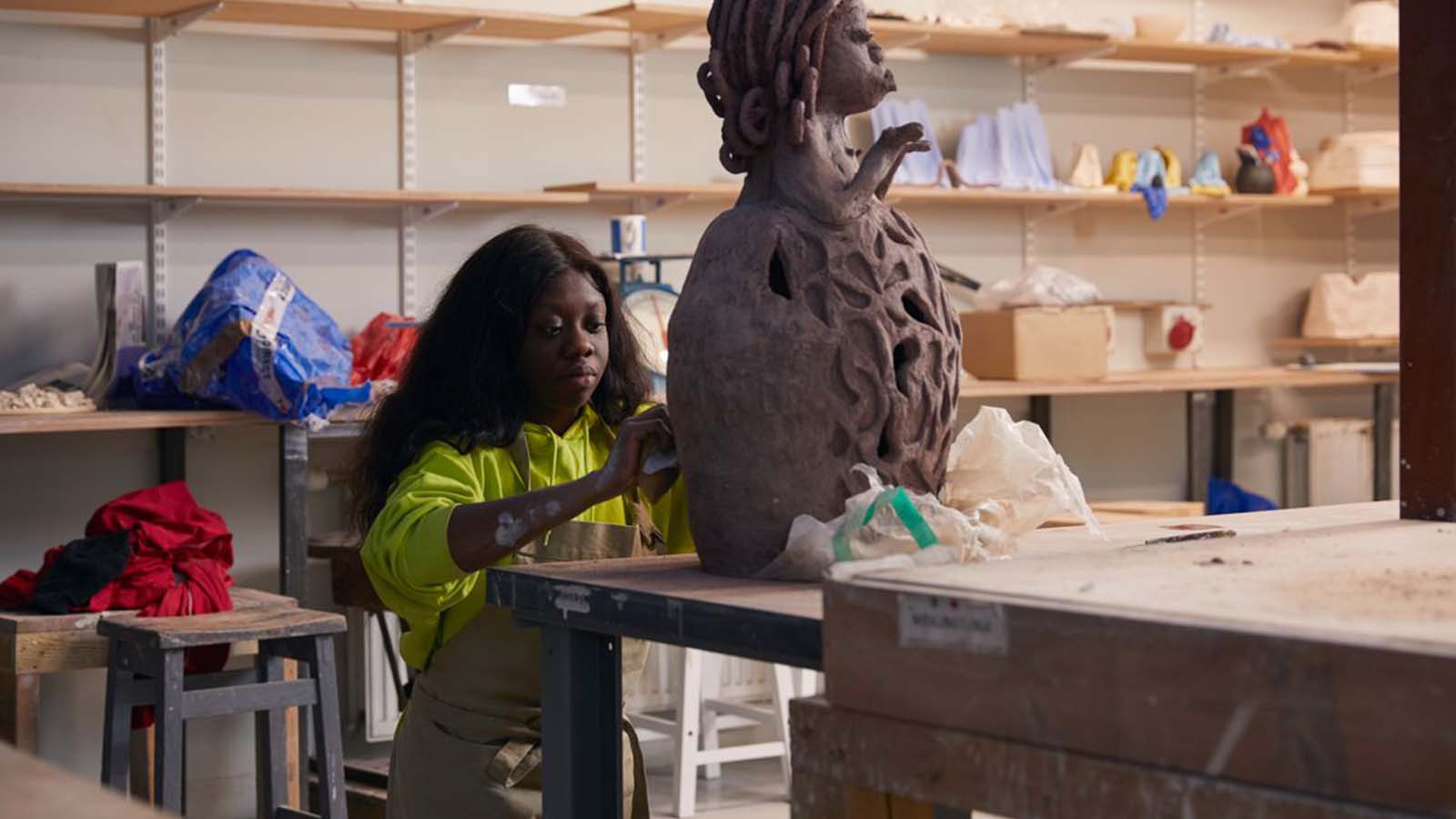 A British Nigerian woman (Josie KO) working on a sculpture in a workshop